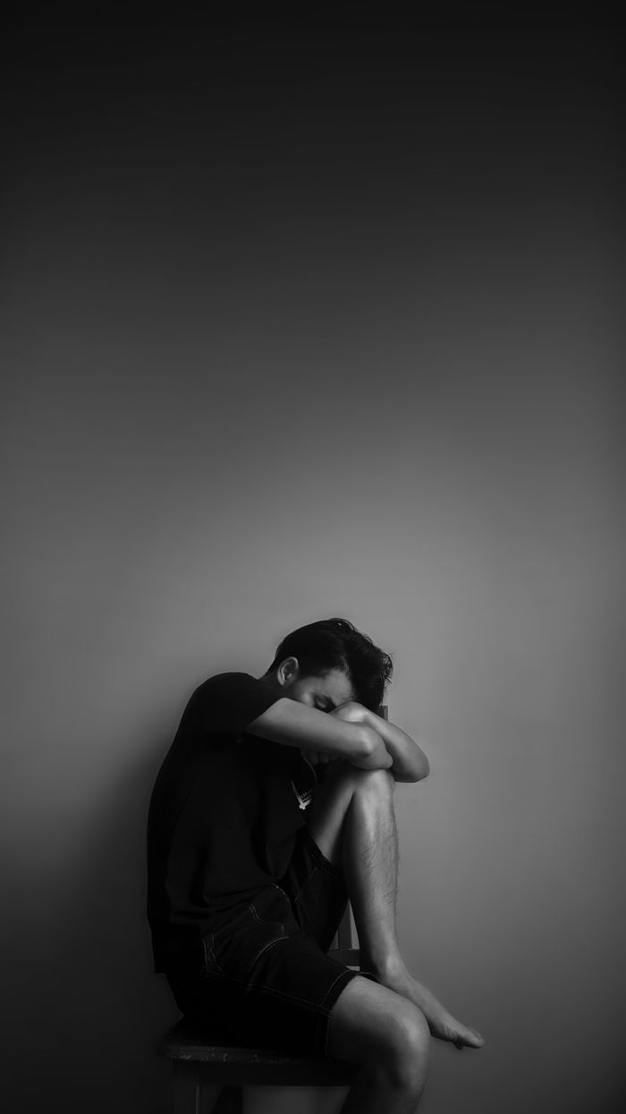 A black and white portrait of a man sitting alone, evoking emotion and contemplation.