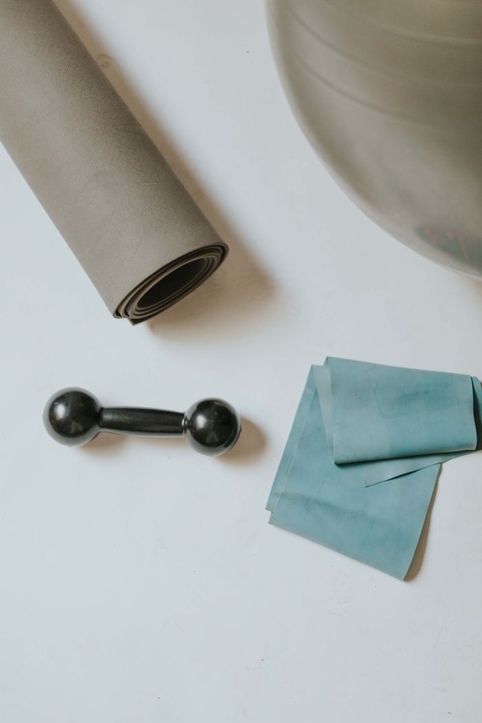 Yoga mat, dumbbell, resistance band, and exercise ball arranged neatly for workout inspiration.